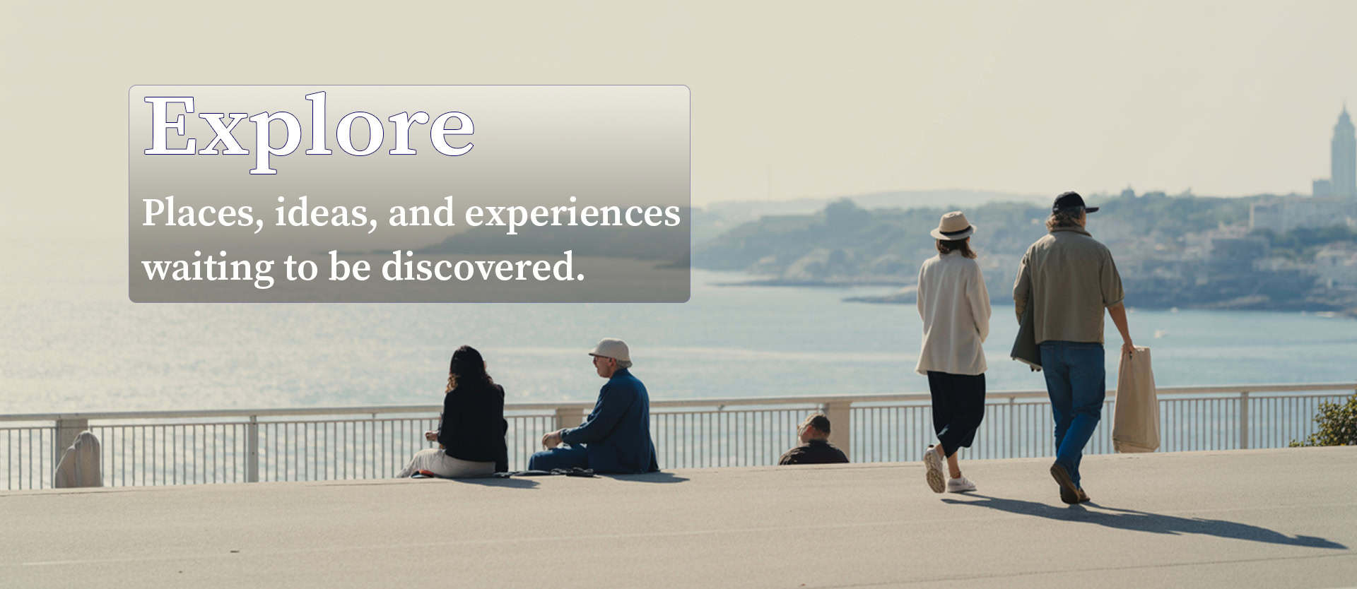 People walking along a waterfront promenade with city skyline in the background.